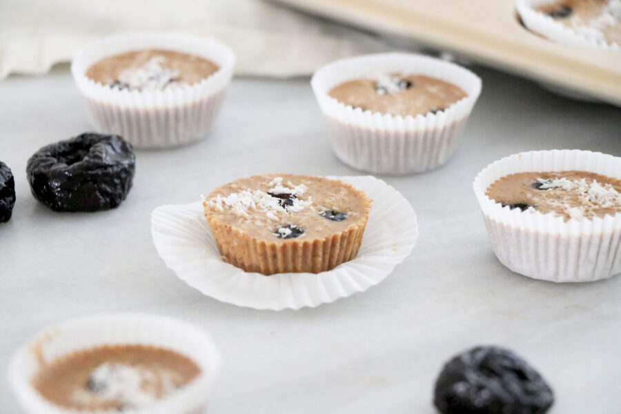 Almond butter prune cups on counter with prunes next to them.