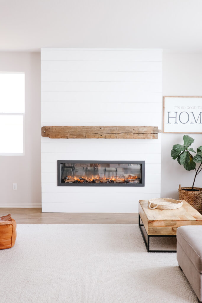 Beautiful Shiplap Fireplace with modern electric fireplace and barn wood beam mantel and fiddle leaf fig tree