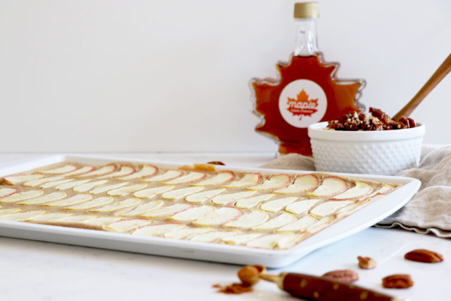 Sheet pan with pancakes and maple syrup in background.