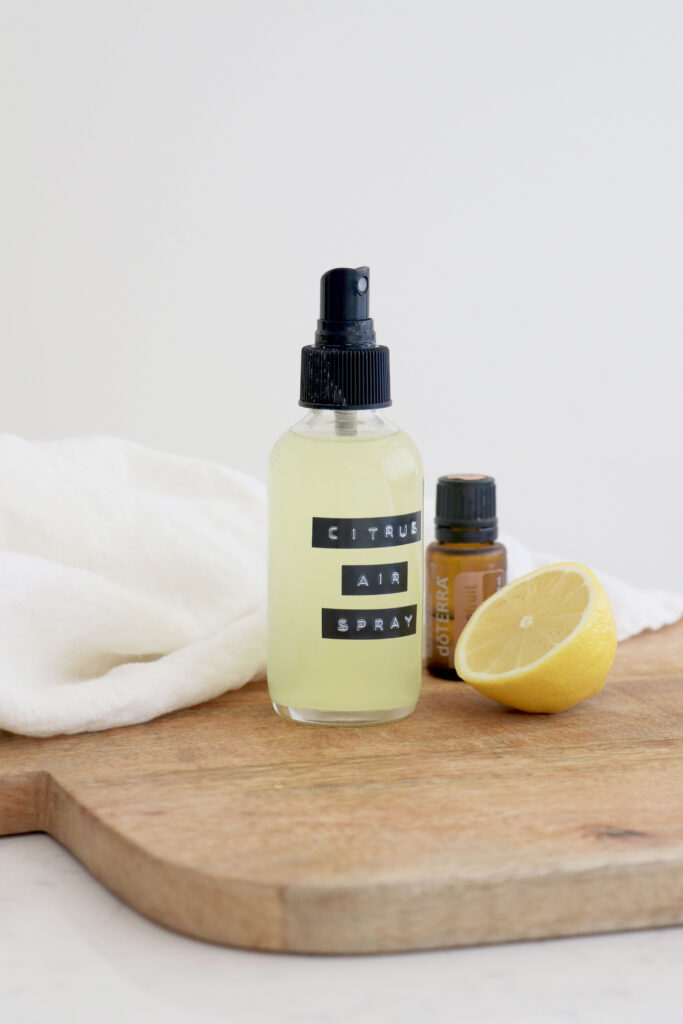 Wooden plank with spray bottle, essential oil bottle and half a lemon.