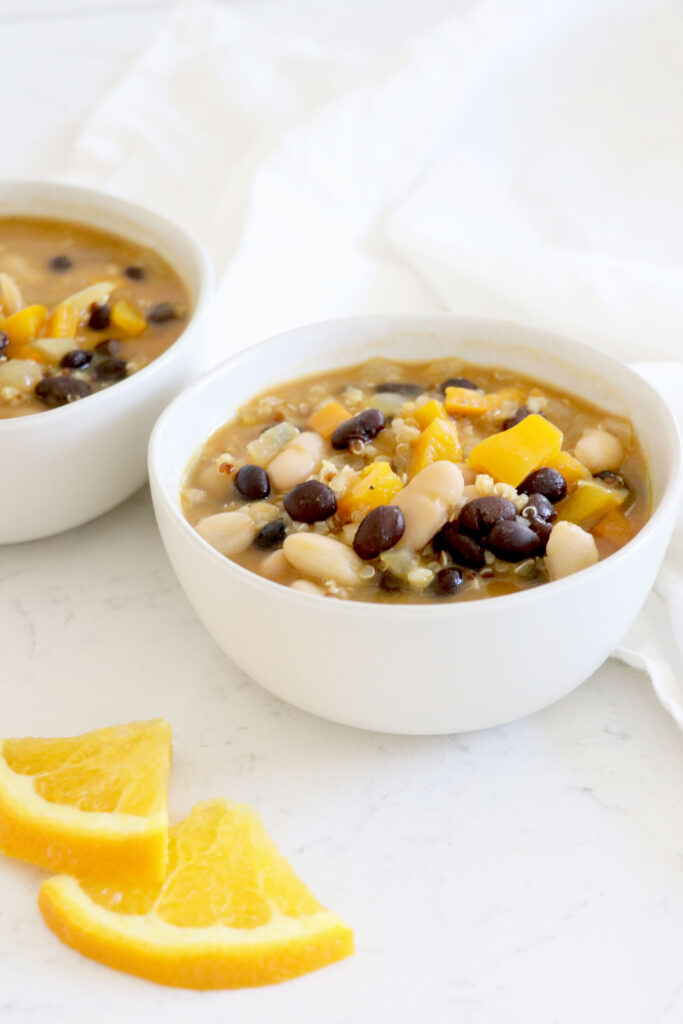 Two bowls of chili with black beans, sweet potato, quinoa and white beans.