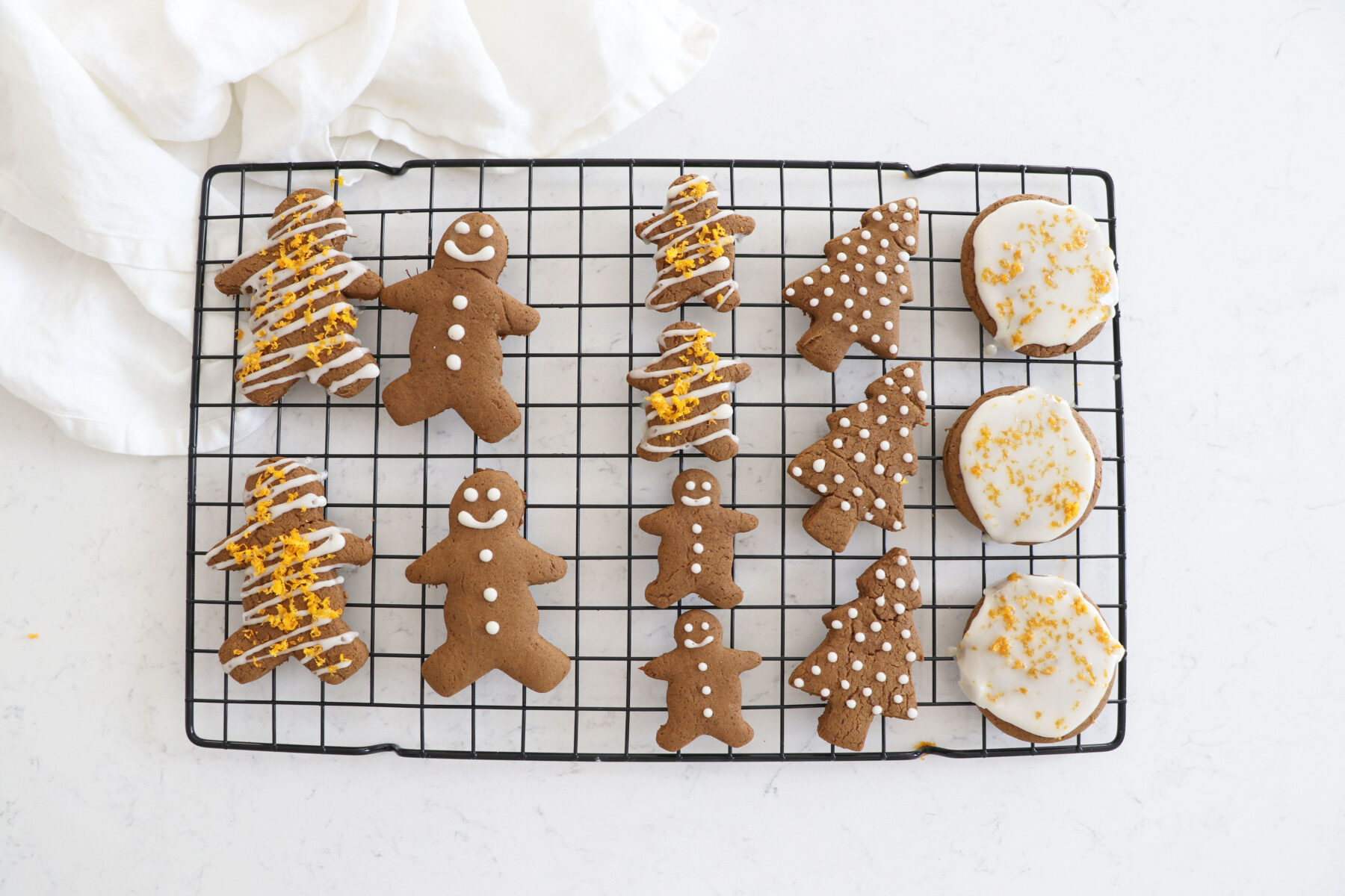 Wire rack with different gingerbread cookies decorated with frosting.