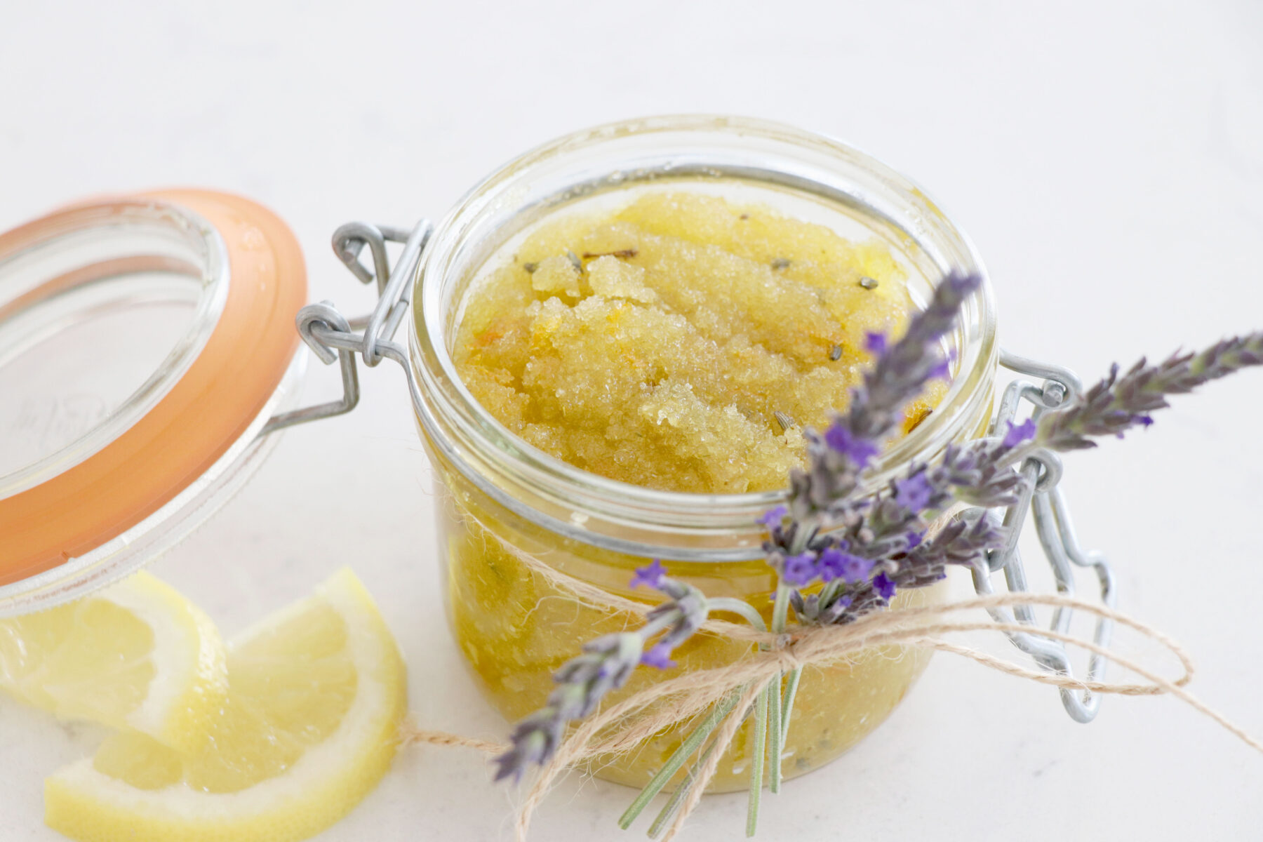 Glass container with sugar scrub that containers lavender and lemon.