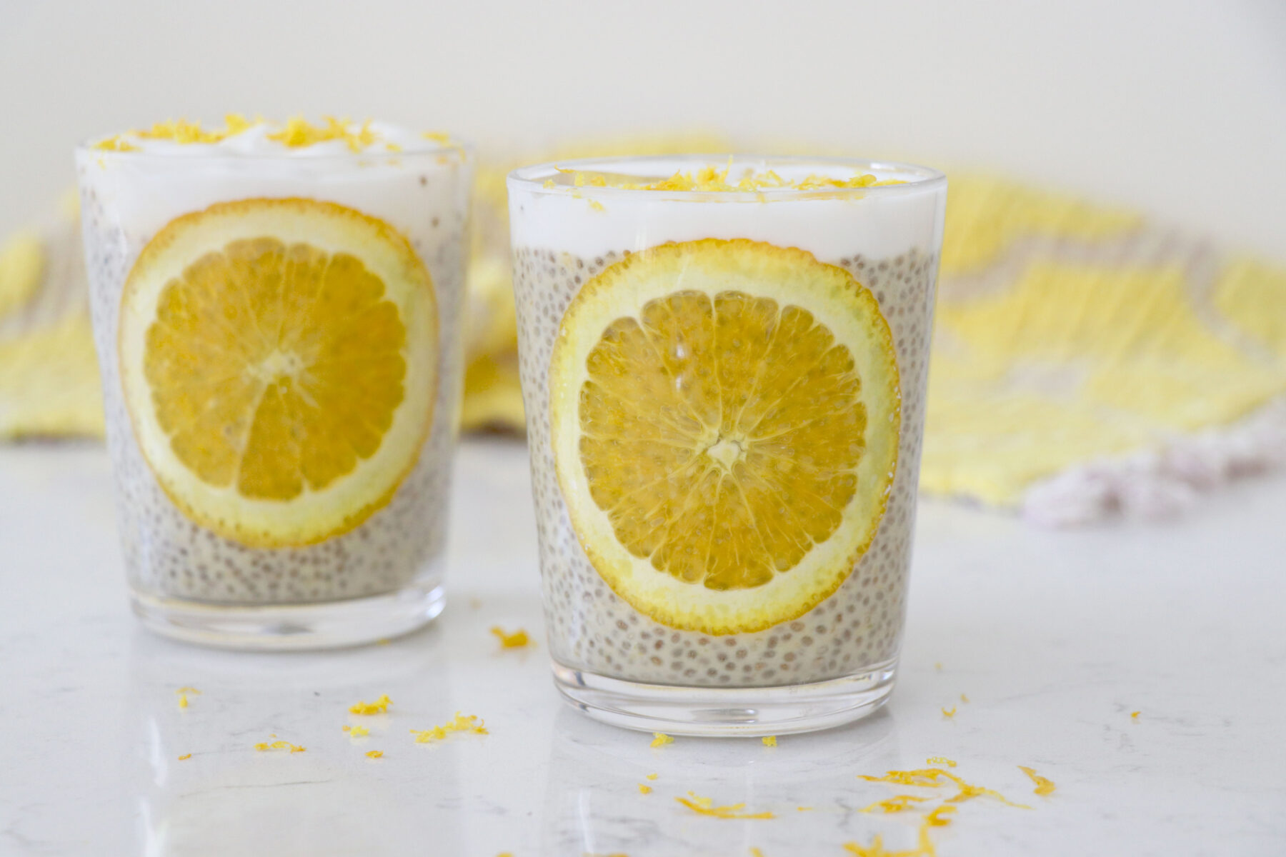 Two glass jars of chia pudding with lemon slices on the side.