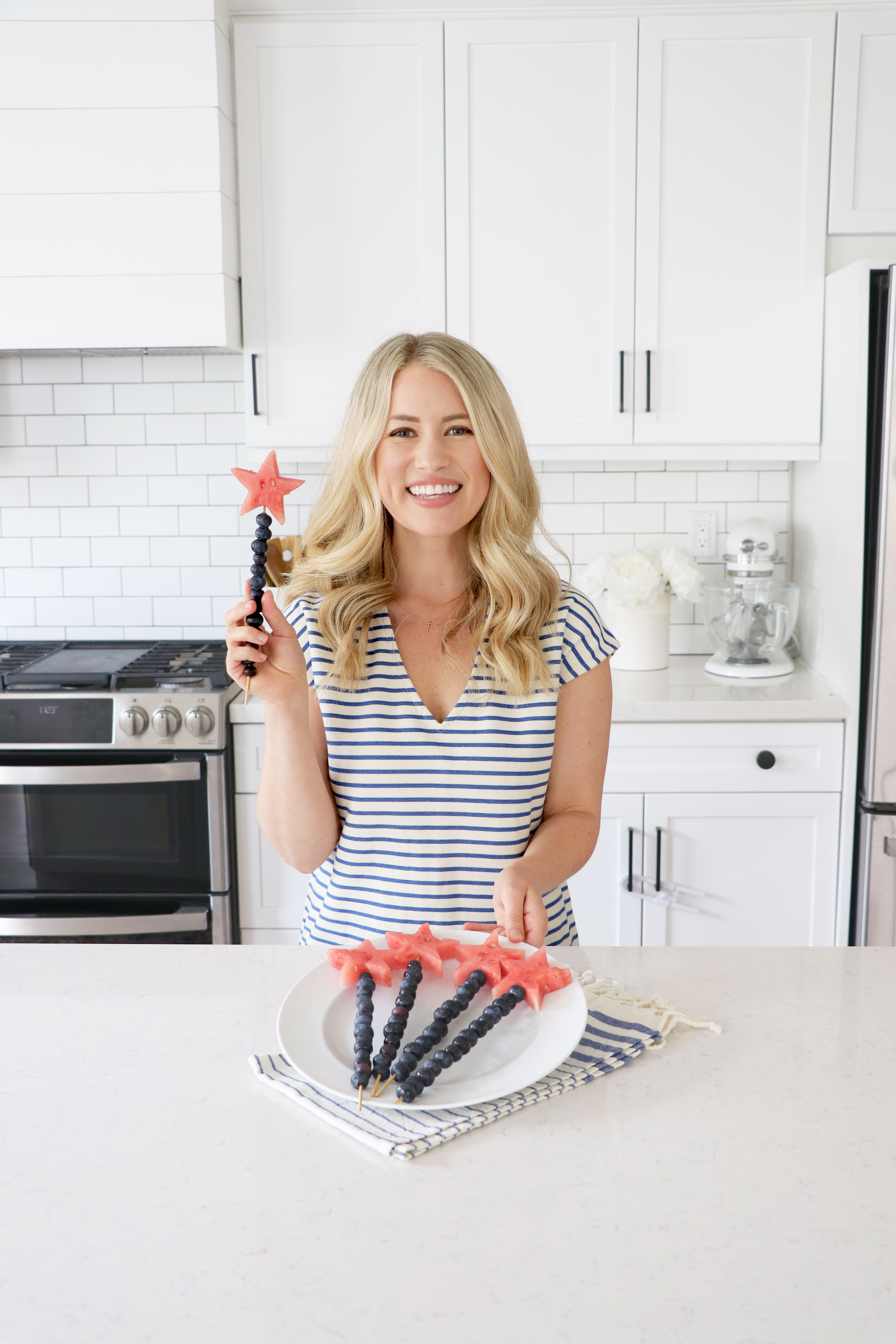 Registered Dietitian in white kitchen holding a wand made of fruit