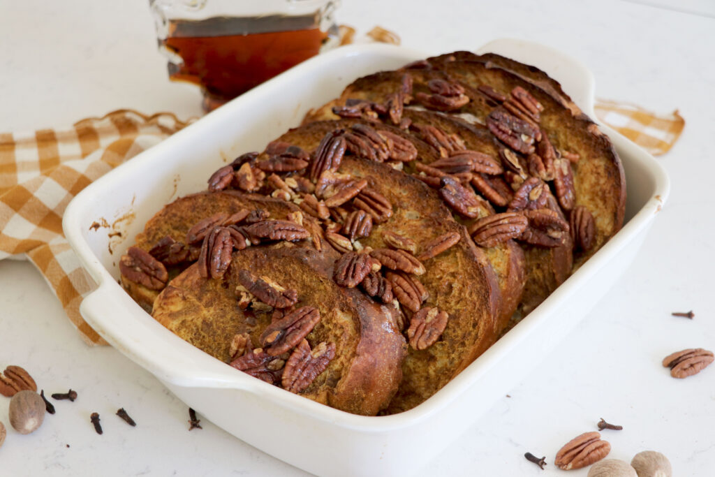White baking dish with baked french toast and pecans